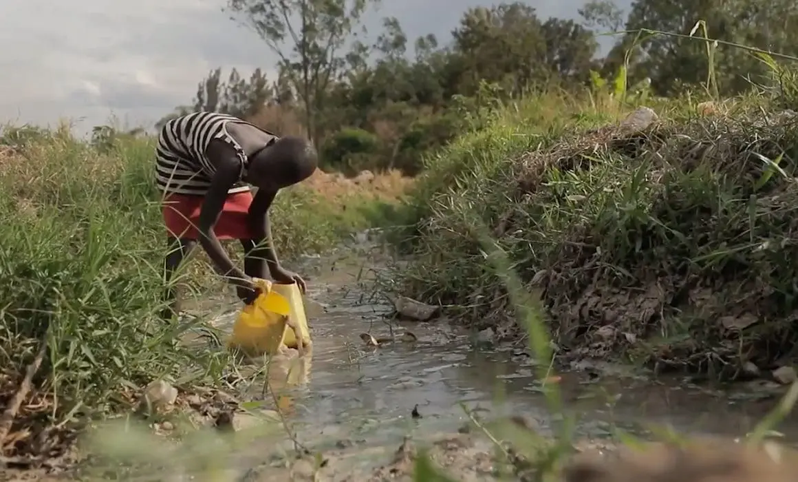 A child collecting water from a stream.