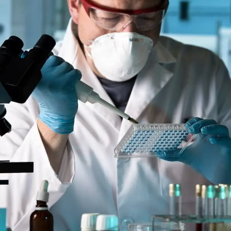 scientist wearing gloves and mask filling test tubes in a lab | Donate to Israel | Support the Technion