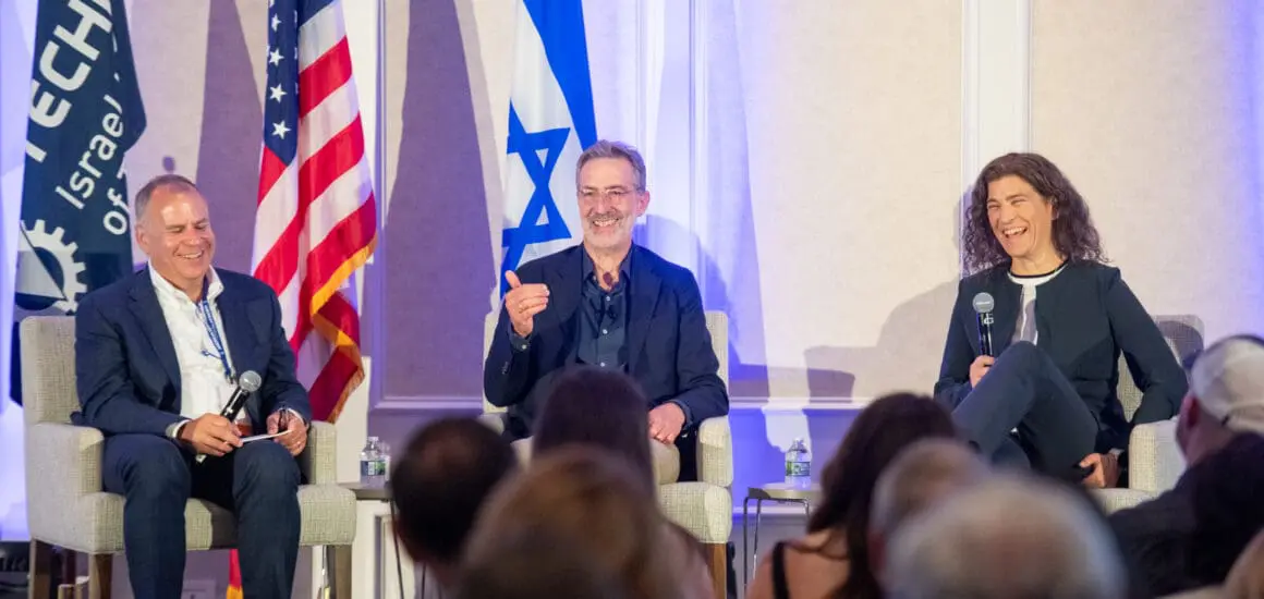 Events Keynote speakers sitting on a stage with a Technion, Israel, and American flag behind them