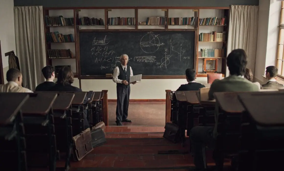 a man standing in front of a chalk board teaching a class