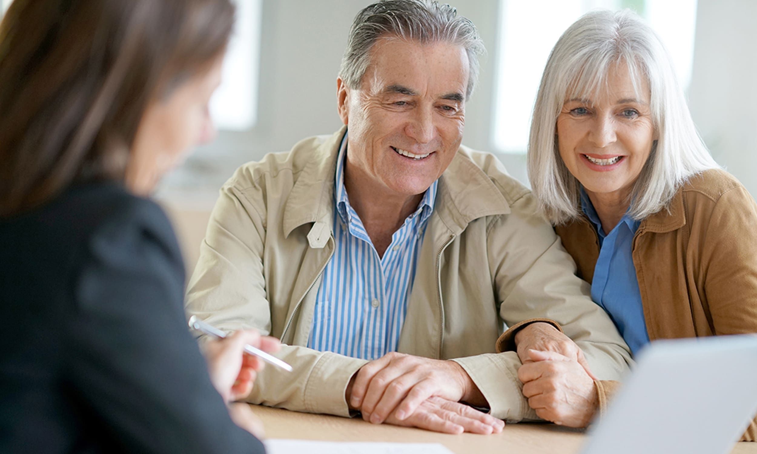 An elderly couple looking at a computer screen with a business woman.