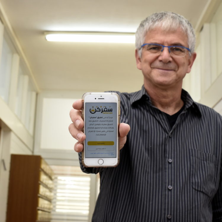 Technion professor holding an iPhone to the camera with a Hebrew website visible.