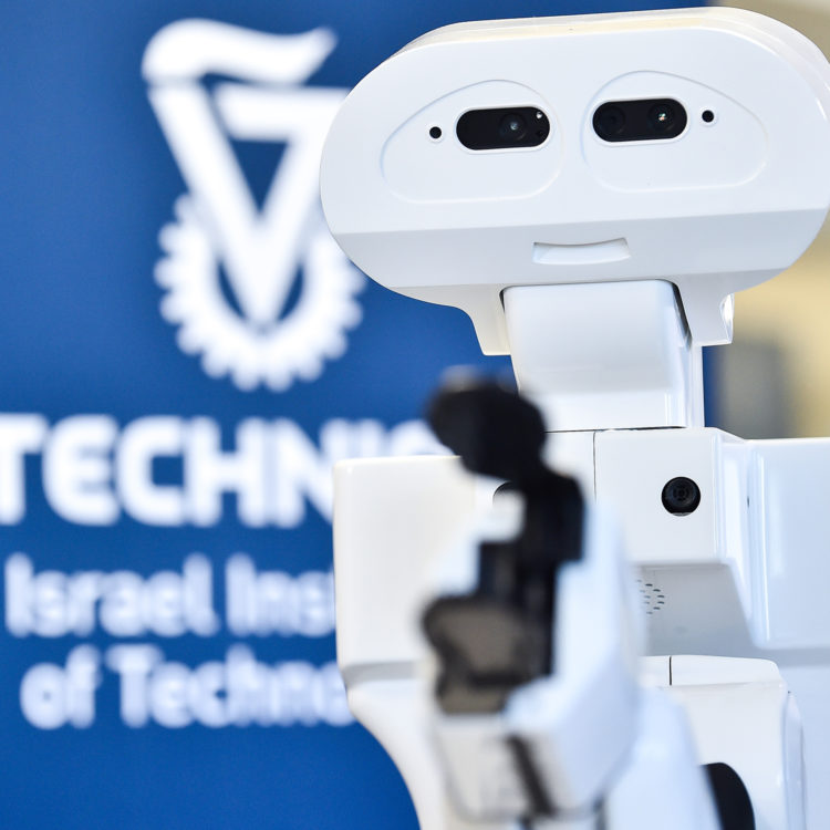 A close-up of a robot with the Technion logo in the background.