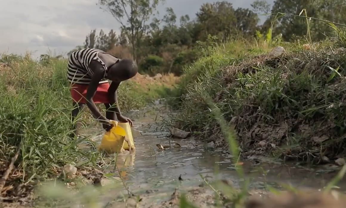 A child collecting water from a stream.