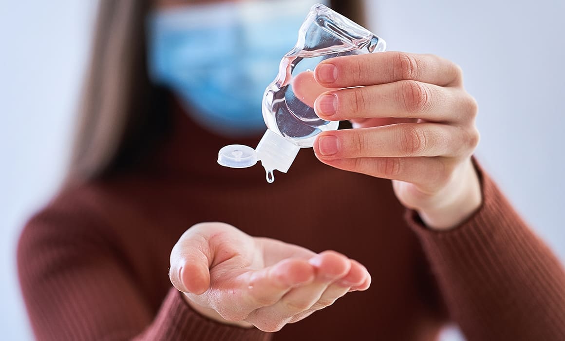 woman wearing mask and red sweater squeezing hand sanitizer gel into her hand | Donate to Support the Technion Israel | American Technion Society