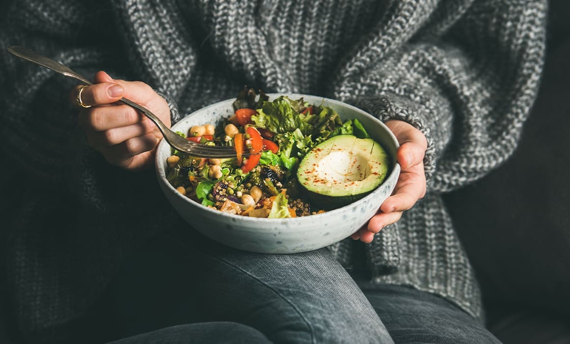 plant-based food and avocado in a white bowl held by woman in grey sweater and dark jeans | Donate to Support the Technion University | American Technion Society