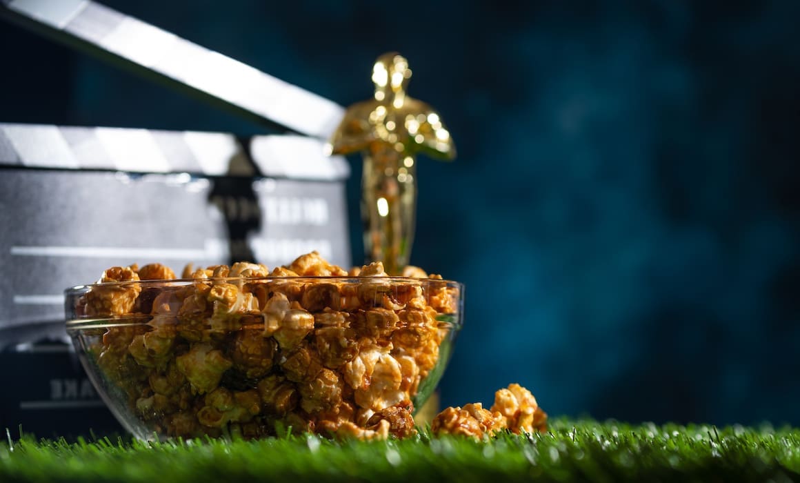 oscar award statue with popcorn bowl and movie clapper on a green surface with black background | Donate to Support Israel | American Technion Society