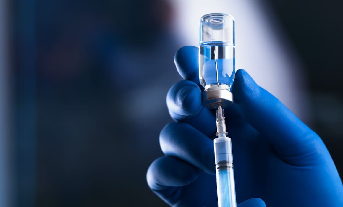 covid-19 vaccine in a glass vial with needle and doctor's gloved hand | Donate to Support Israel | Technion University