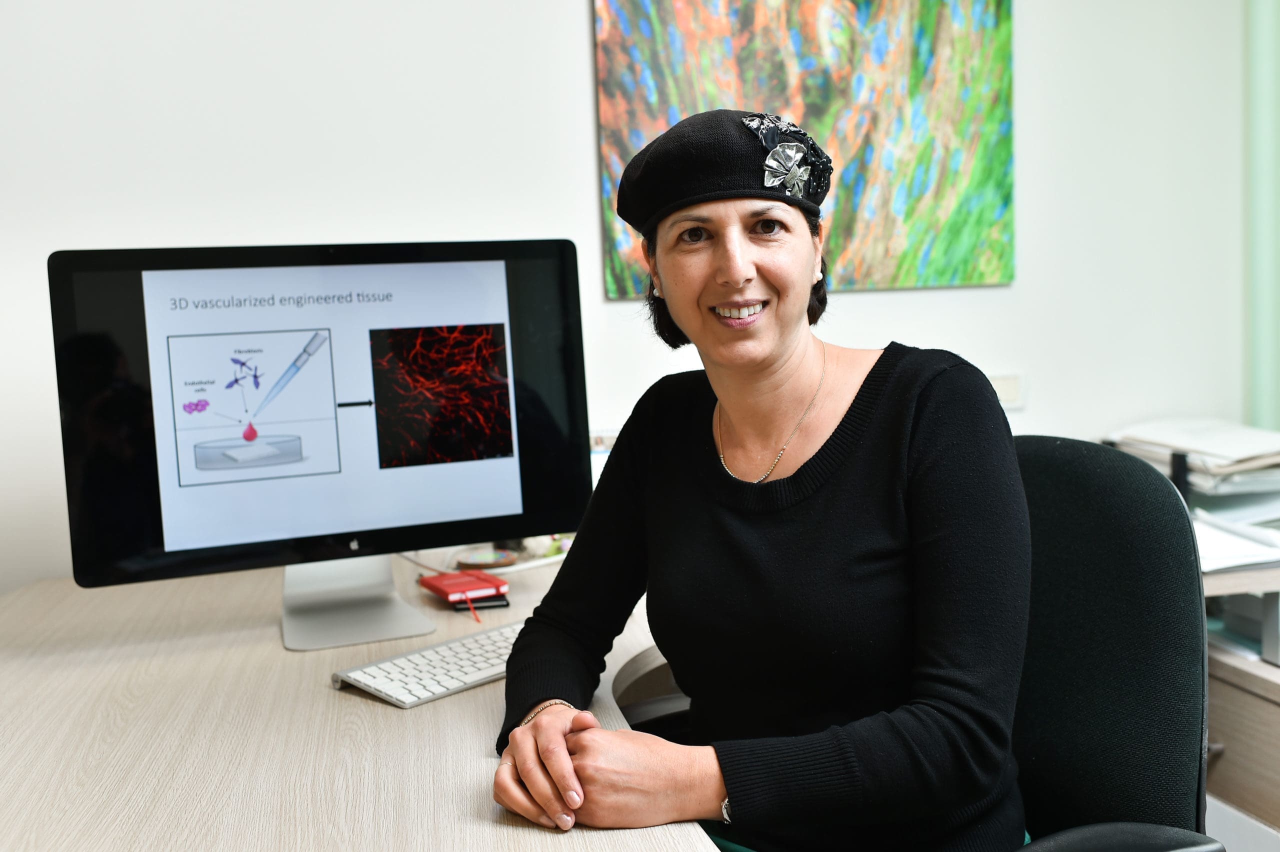 technion professor shulamit levenberg, cultivated meat entrepreneur, sitting in front of a desktop computer in an office wearing black sweater and black beret | Donate to Technion Israel | Support the Technion University | American Technion Society