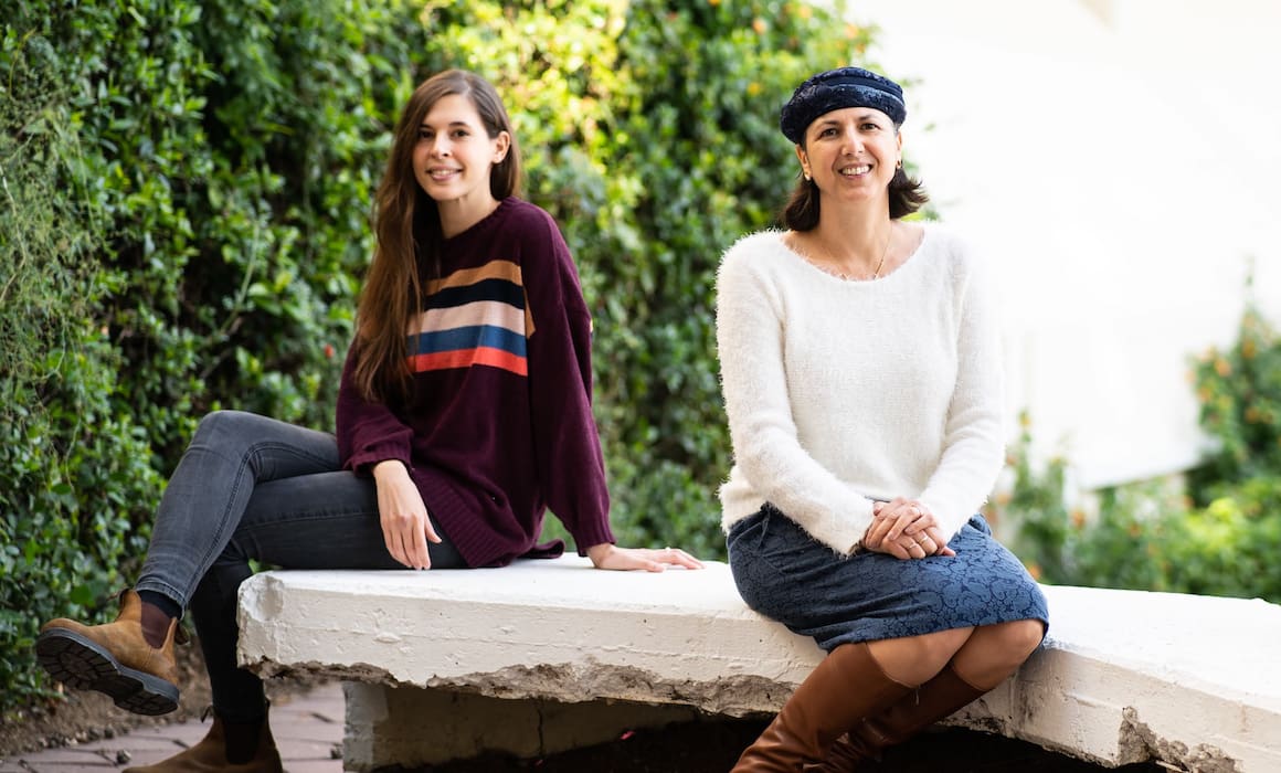 technion prof shulamit levenberg and ph.d. student Iris Ianovici on a stone bench outside with green bushes in background, cultivated meat researchers | Donate to Support Israel | American Technion Society | Technion University