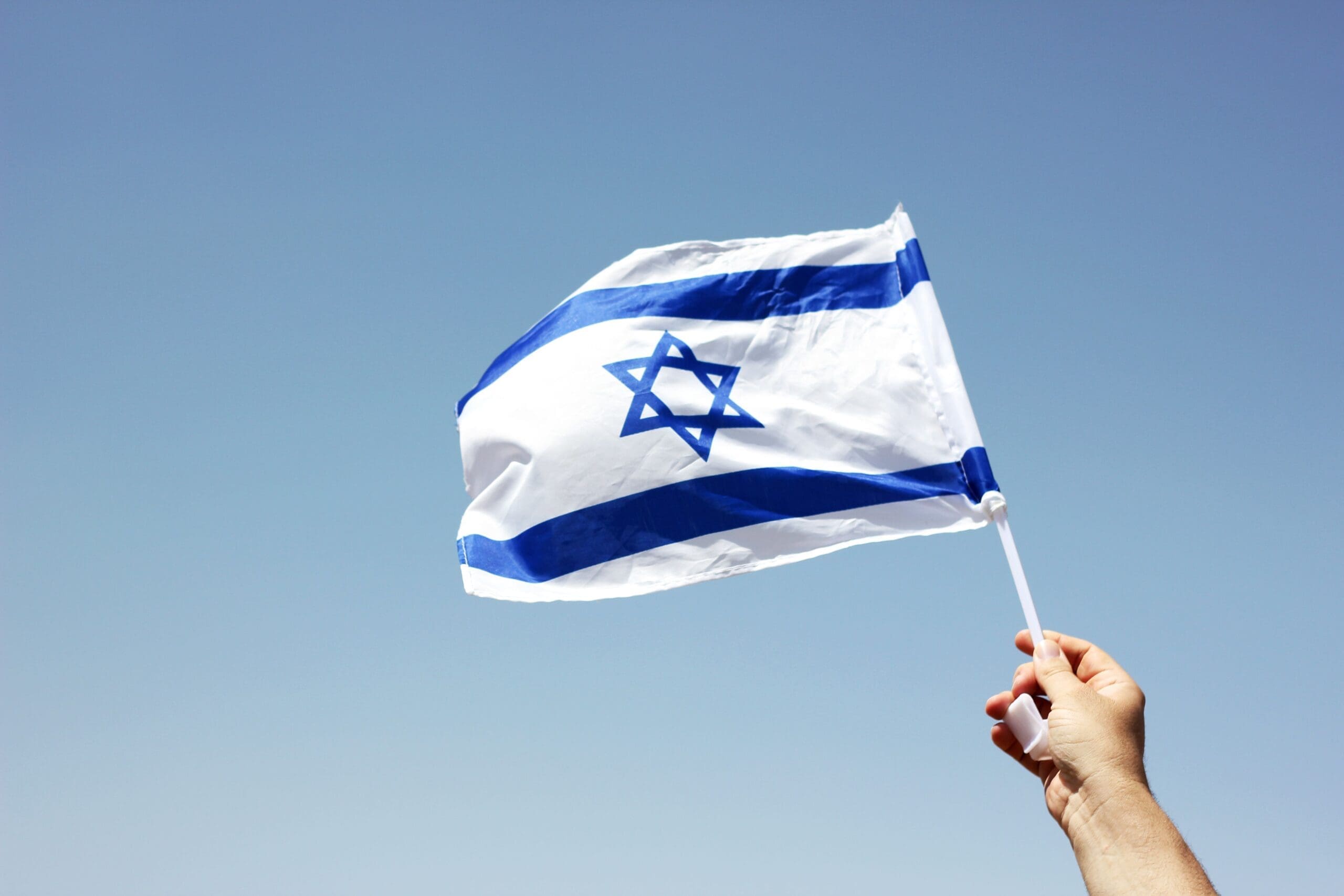 to be israeli | hand holding israeli flag up in the blue sky | Donate to Support Israel | American Technion Society | Technion University