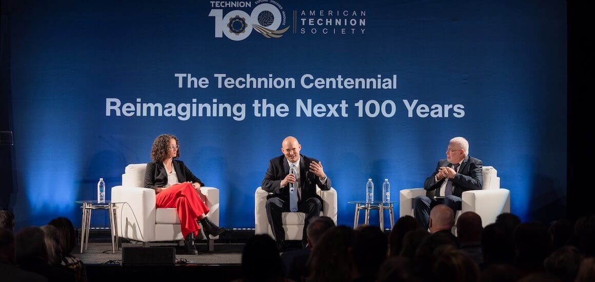 Keynote speakers sitting on a stage with a dark background