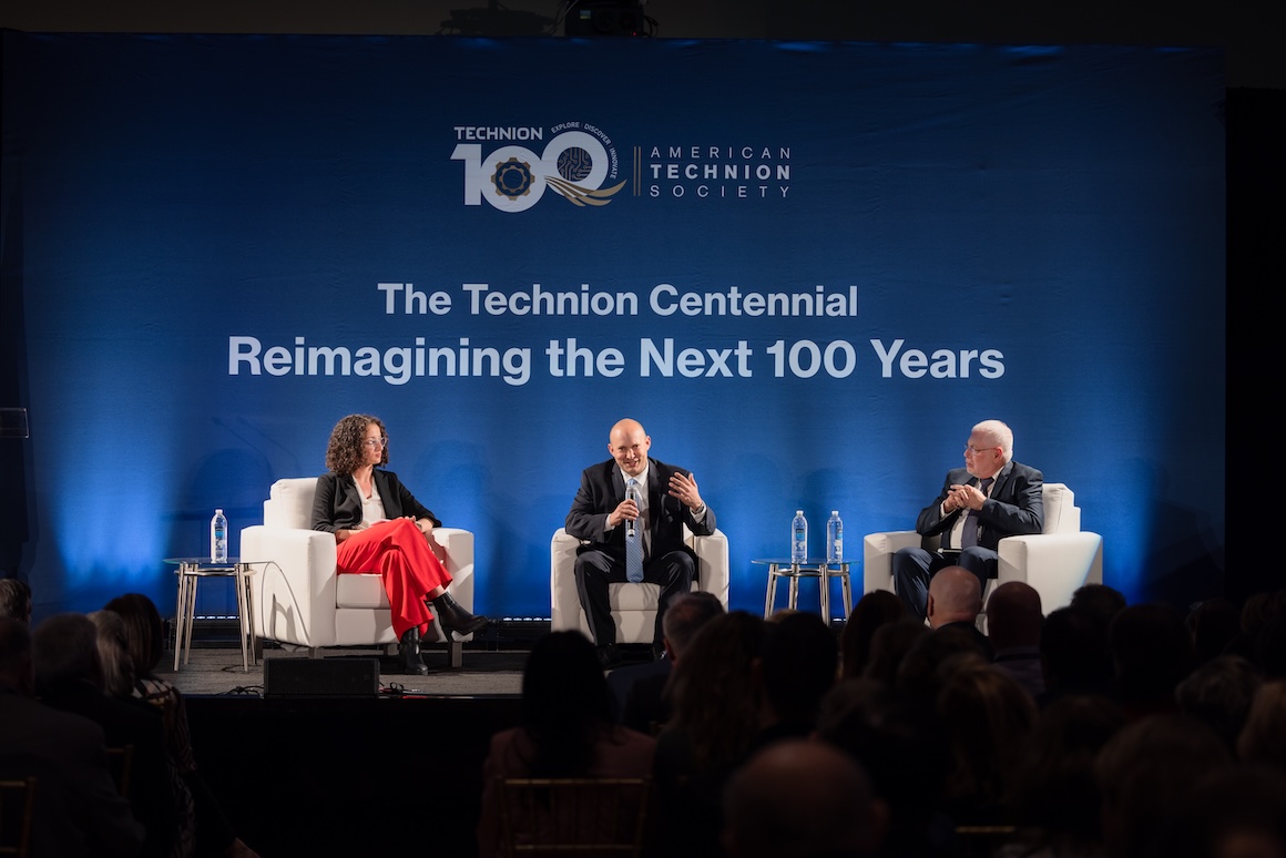 Keynote speakers sitting on a stage with a dark background