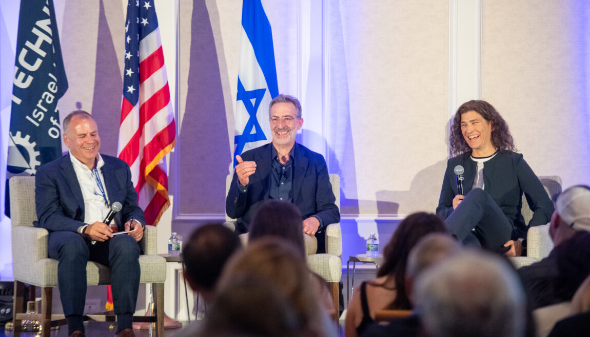 Keynote speakers sitting on a stage with a Technion, Israel, and American flag behind them