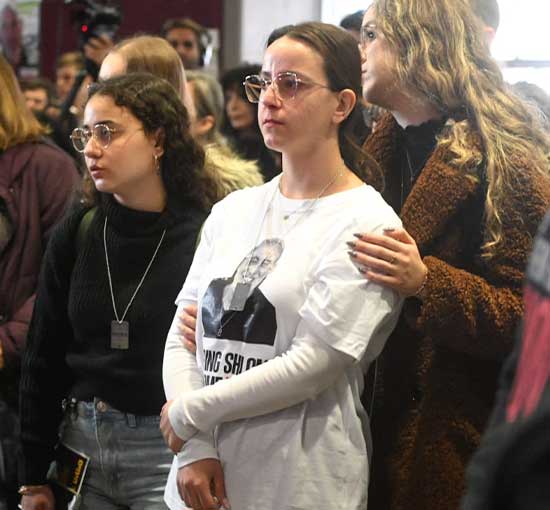 Girl standing amongst others in a somber setting