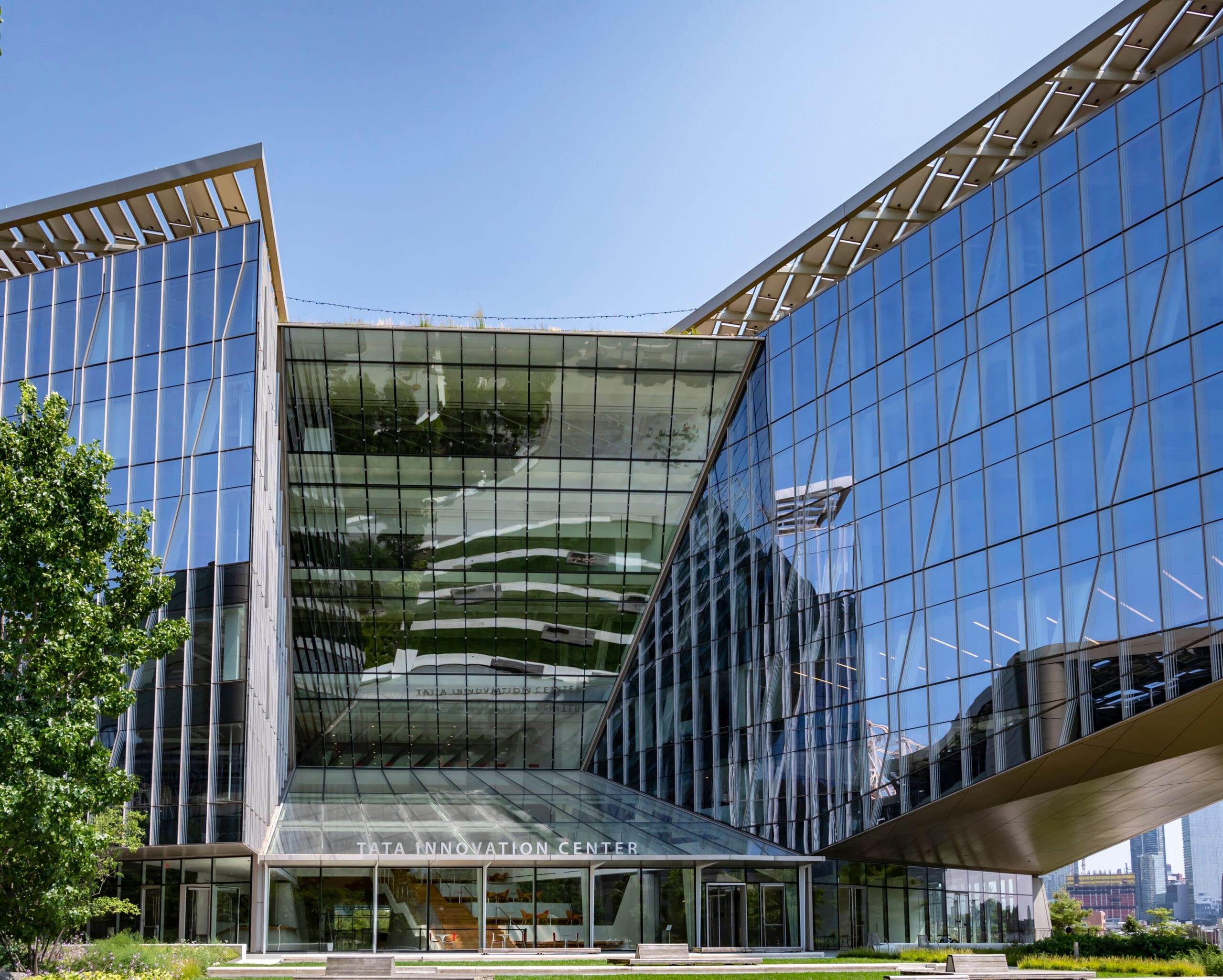 Photo of large glass building with blue sky backdrop, Tata Innovation Center at Jacobs Institute Cornell Tech