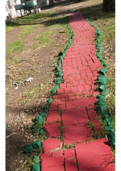 red brick trail in the grass with green details on either side