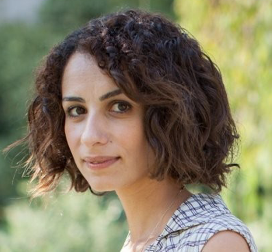 Headshot of Liat Maoz from slight side angle in front of a green nature background.