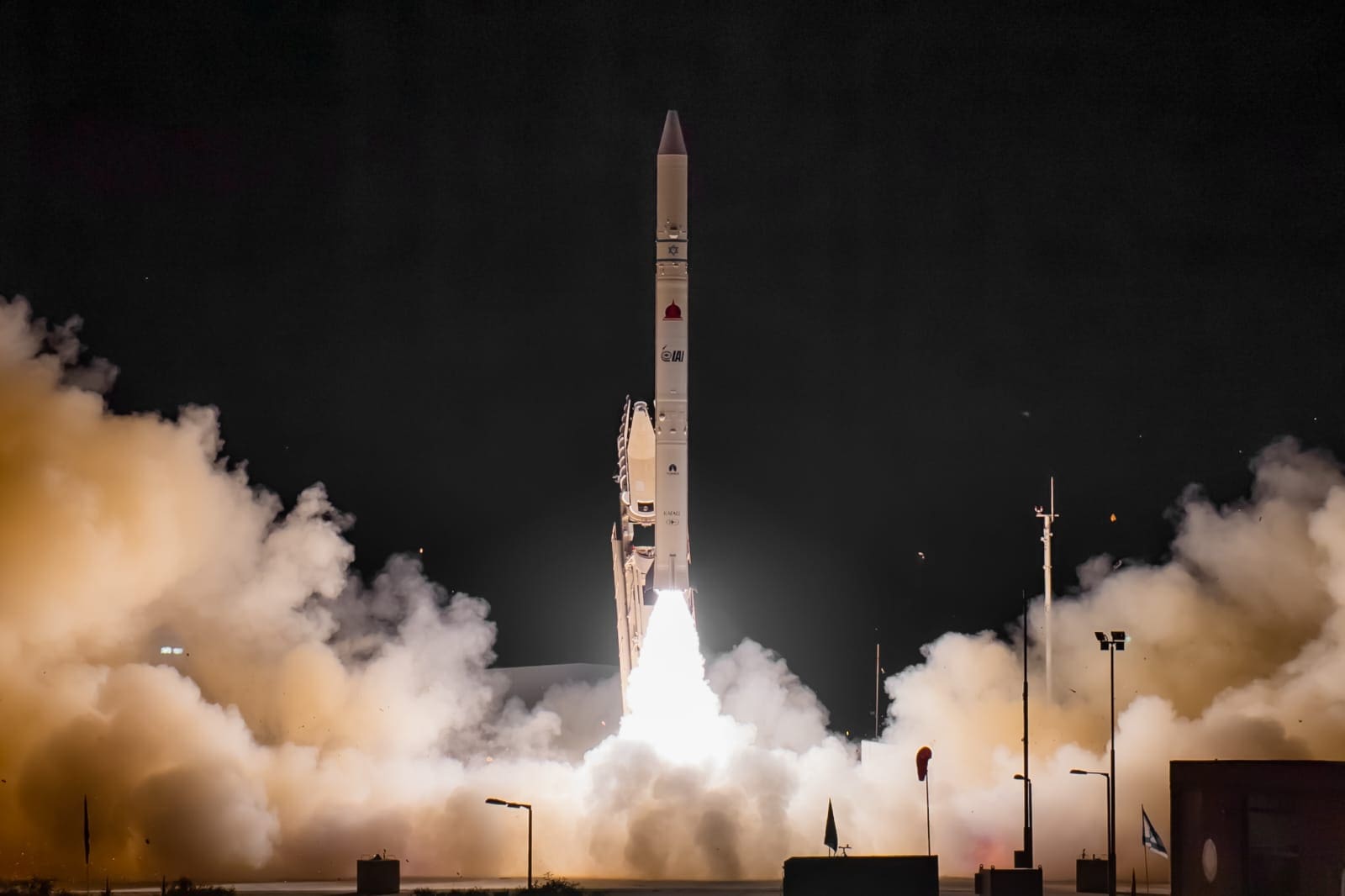rocket in mid-launch at nighttime with flames and smoke billowing from its engines.