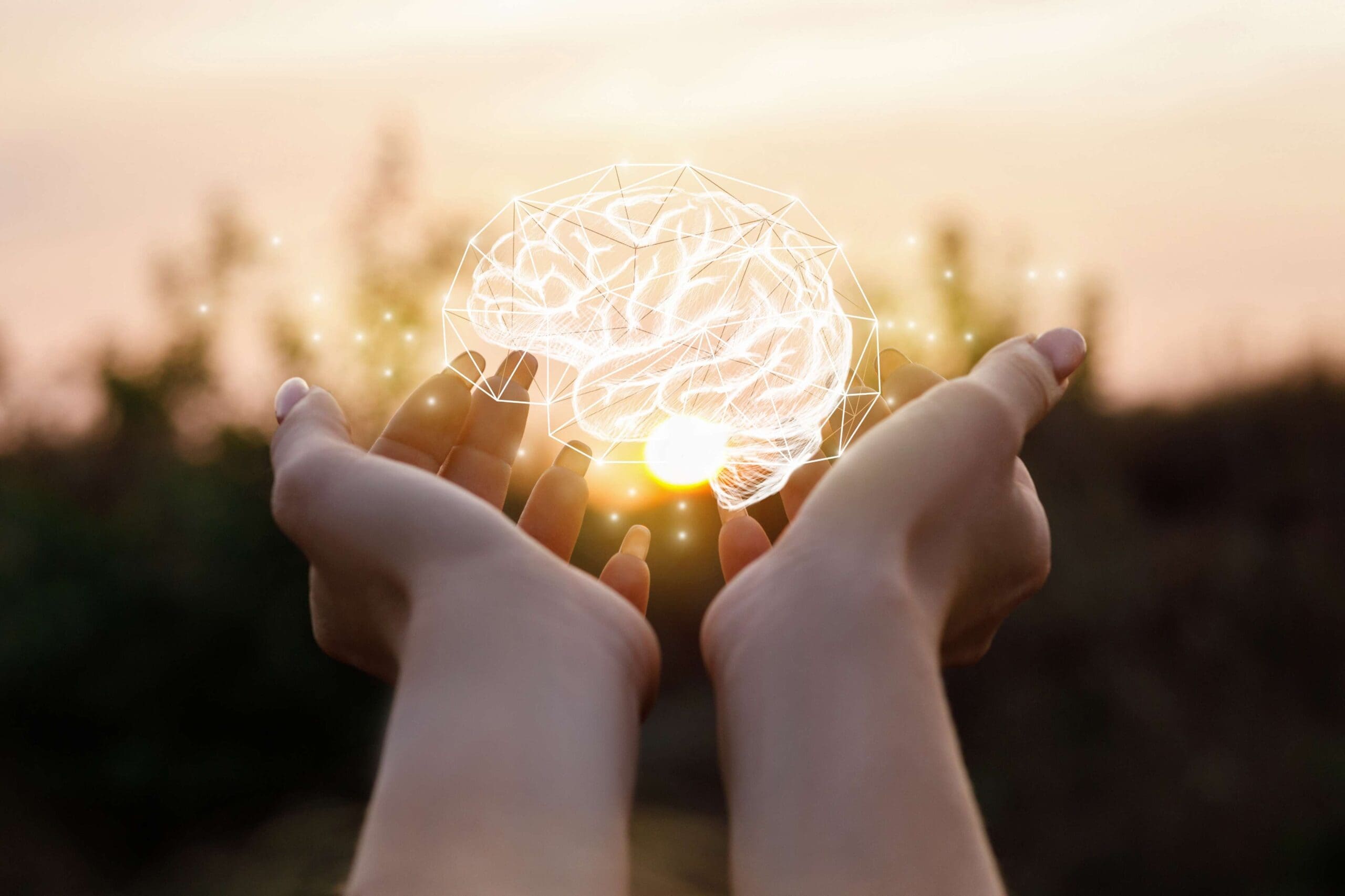 rendered image of a glowing brain hologram floating in between two outstretched hands with trees and evening sky in blurred background